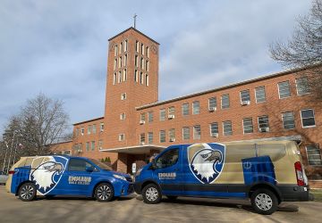 Emmaus vans in front of campus clocktower