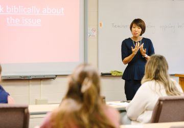 Female Faculty Standing at Whiteboard Teaching