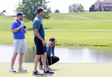 Two standing golfers and one crouching