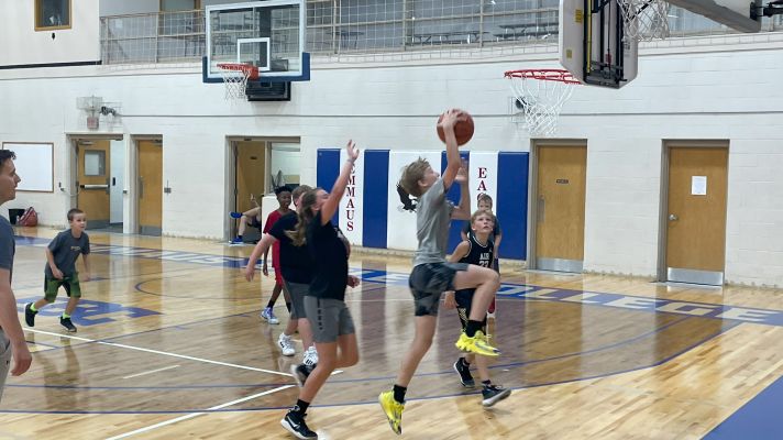 Middle school boy makes a basketball layup